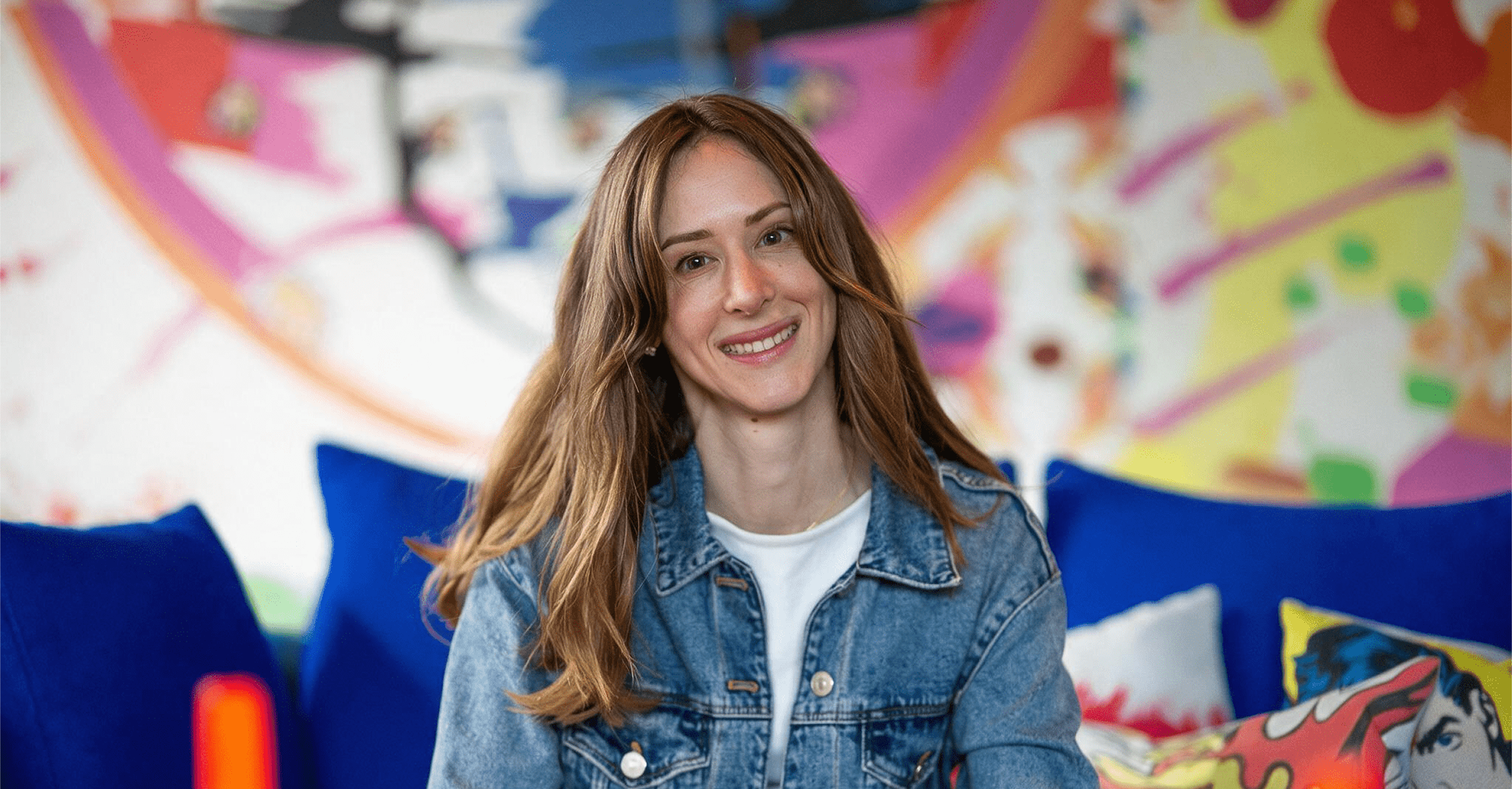 Camille Brunette smiling, sitting in front of a colourful mural